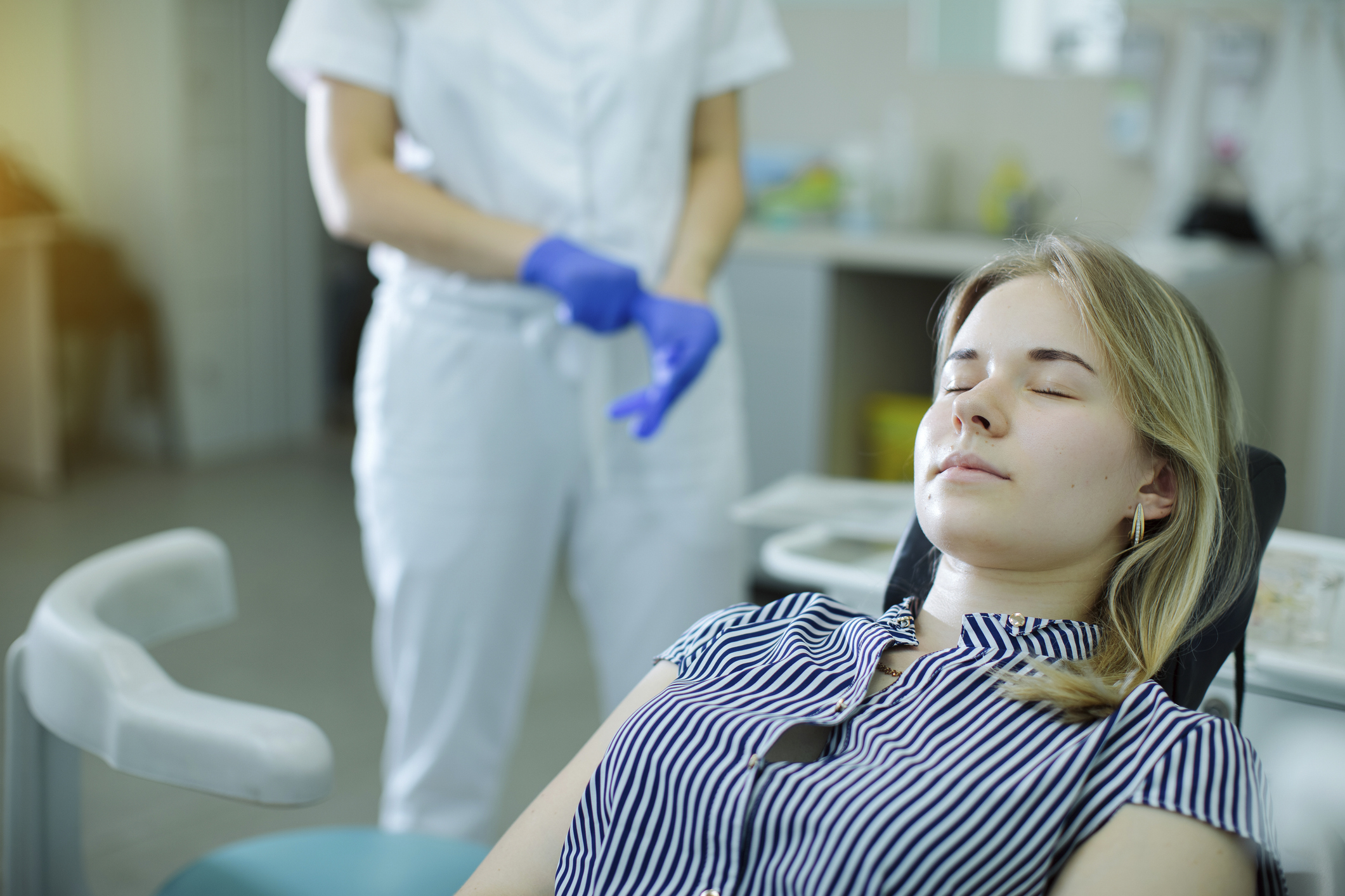 the patient, lying in the dental chair, waits for the dentist to come up to the chair and putting on gloves